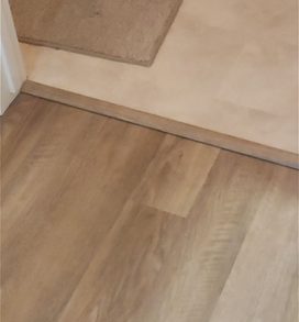 New plank flooring at a bathroom doorway with trim