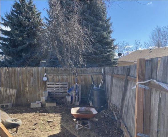 Leaning, broken wood fence along a side yard