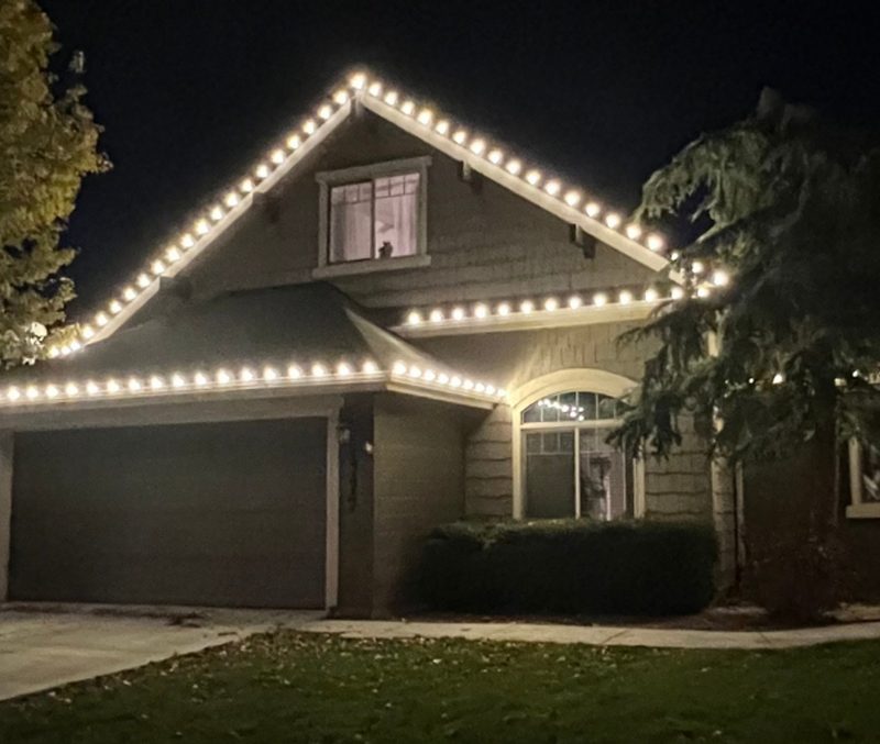 Two-storey house outlined in warm white holiday lights at night