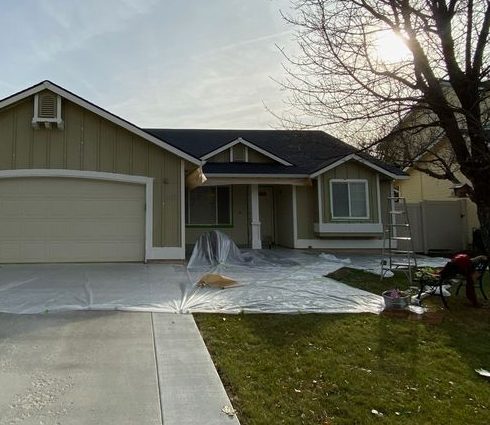 Tan single-storey house with a two-car garage before repainting