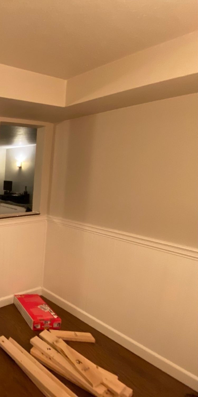 Bedroom corner with bare walls and trim boards on the floor